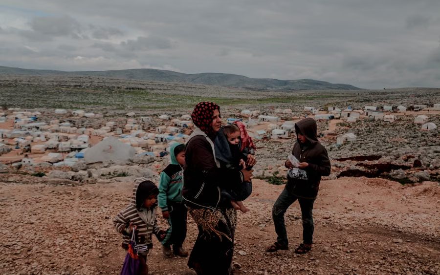 A mother with her baby and children outside their shelter