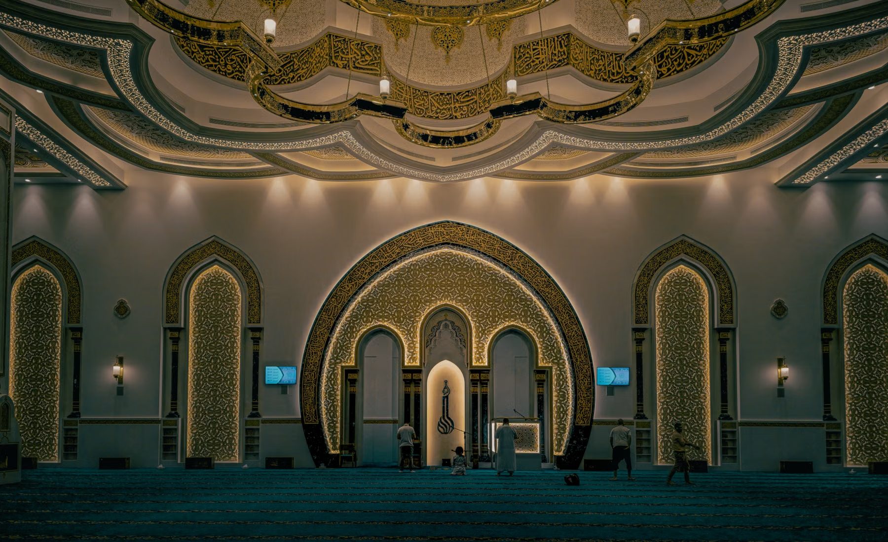 Interior of a mosque, golden arches receding into shadow